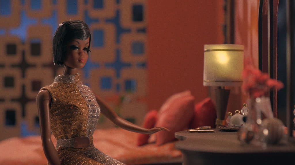 Black Barbie: A Documentary - Stop Motion Black Barbie scene. Julia doll, the predecessor to Black Barbie, sitting on a dollhouse bed, looking through a dollhouse mirror